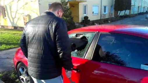 A man breaks his own car’s window after locking keys